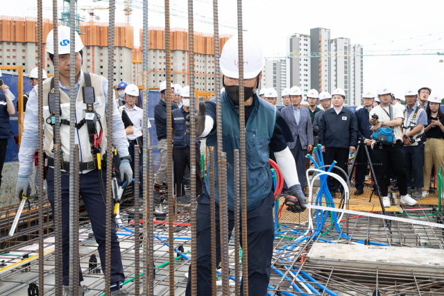 원희룡 국토교통부 장관과 관계자들이 경기 화성시 비봉지구 A-3 BL 공공아파트 공사현장을 둘러보고 있는 장면이 포함돼 있음. 사진에는 콘크리트 위로 철근이 세워져 있는 모습이 있음. 